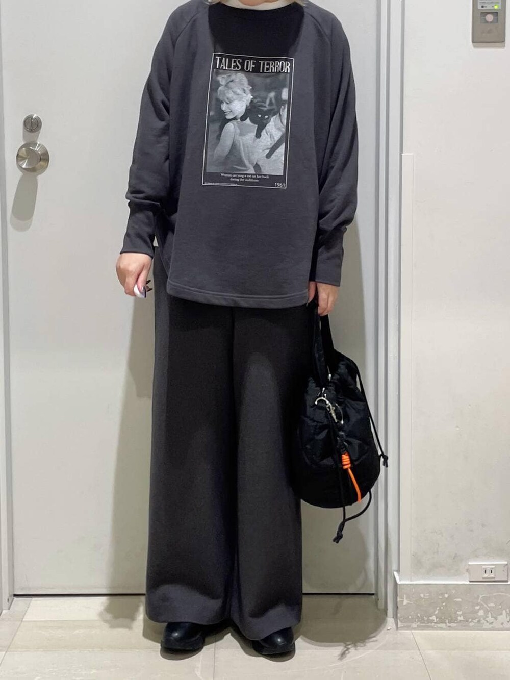 ブラック系のハンドバッグ、ブラック系のブーツ、ホワイト系のTシャツ/カットソーを着用したレディースの秋コーディネートの2枚目の写真