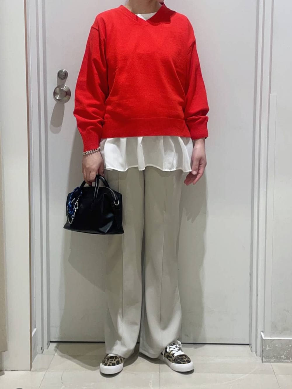 レッド系のニット/セーター、ベージュ系のその他パンツ、ホワイト系のタンクトップを着用したレディースの春コーディネートの2枚目の写真