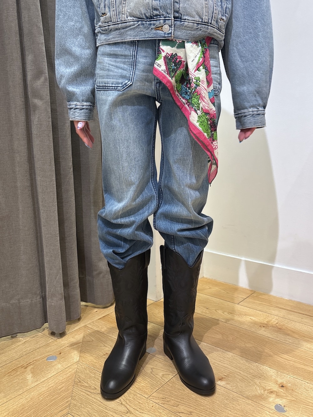 ブルー系のデニムジャケット、ブラック系のブーツ、ブルー系のデニムパンツを着用したレディースの春コーディネートの6枚目の写真