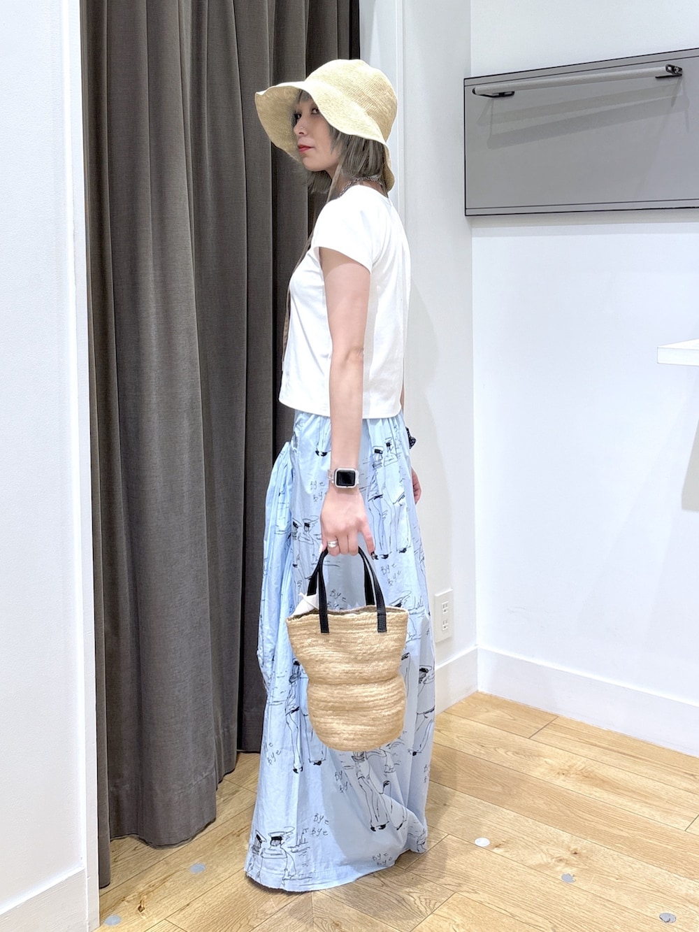 ベージュ系のトートバッグ、ブルー系のスカート、ホワイト系のTシャツ/カットソーを着用したレディースの夏コーディネートの3枚目の写真