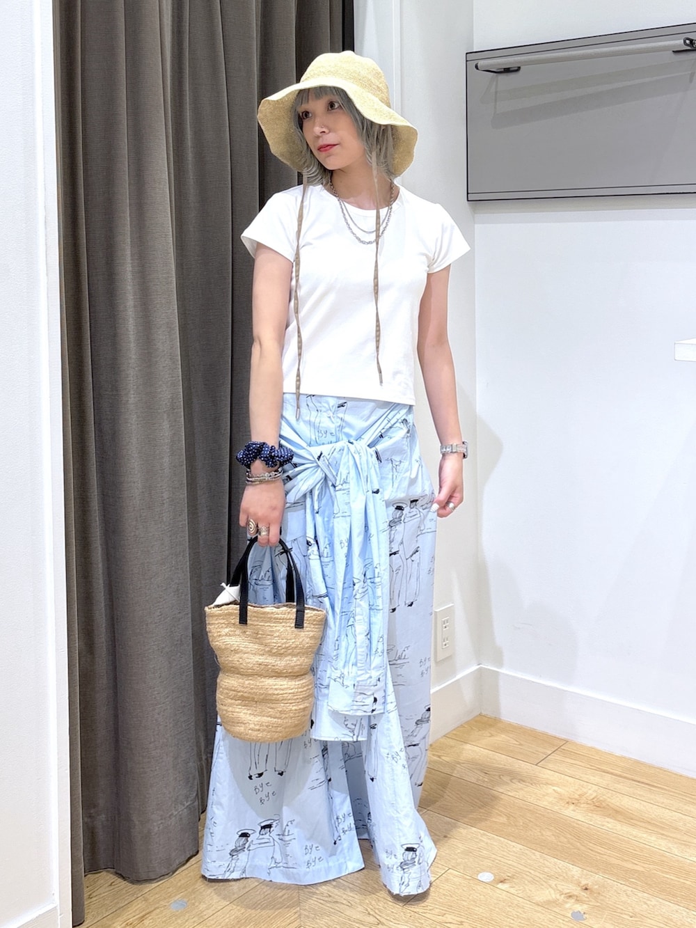 ベージュ系のトートバッグ、ブルー系のスカート、ホワイト系のTシャツ/カットソーを着用したレディースの夏コーディネートの2枚目の写真