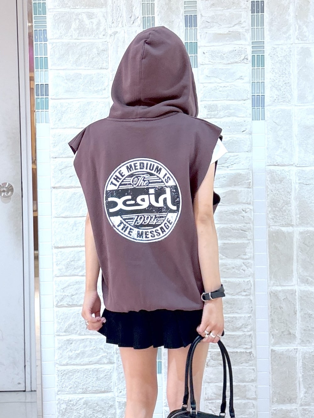 ブラウン系のベスト、ブラック系のスカート、ブラック系のハンドバッグを着用したレディースの夏コーディネートの8枚目の写真