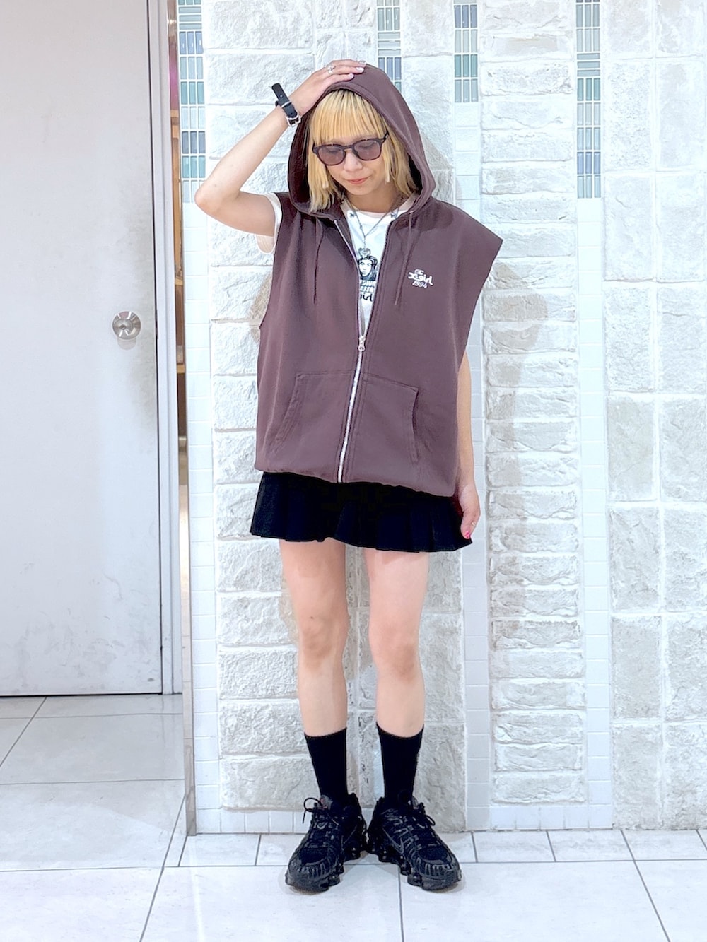 ブラウン系のベスト、ブラック系のスカート、ブラック系のハンドバッグを着用したレディースの夏コーディネートの4枚目の写真