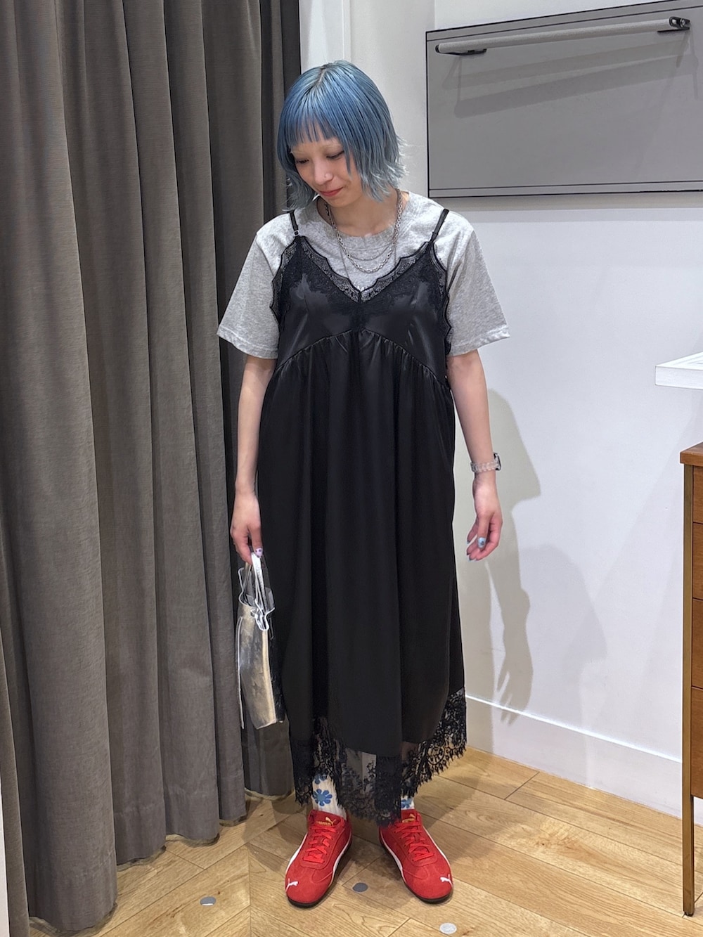 シルバー系のショルダーバッグ、ブラック系のワンピース、レッド系のスニーカーを着用したレディースの春コーディネートの3枚目の写真