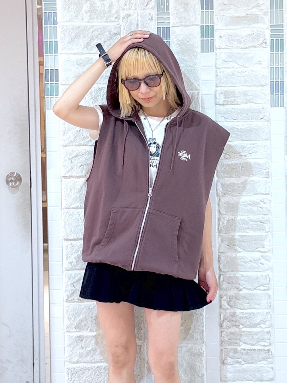 ブラウン系のベスト、ブラック系のスカート、ブラック系のハンドバッグを着用したレディースの夏コーディネートの7枚目の写真