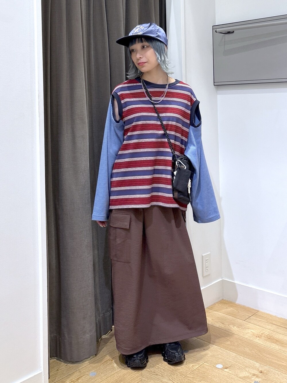 ブラック系のショルダーバッグ、ブルー系のTシャツ/カットソー、ブラウン系のスカートを着用したレディースの夏コーディネートの2枚目の写真