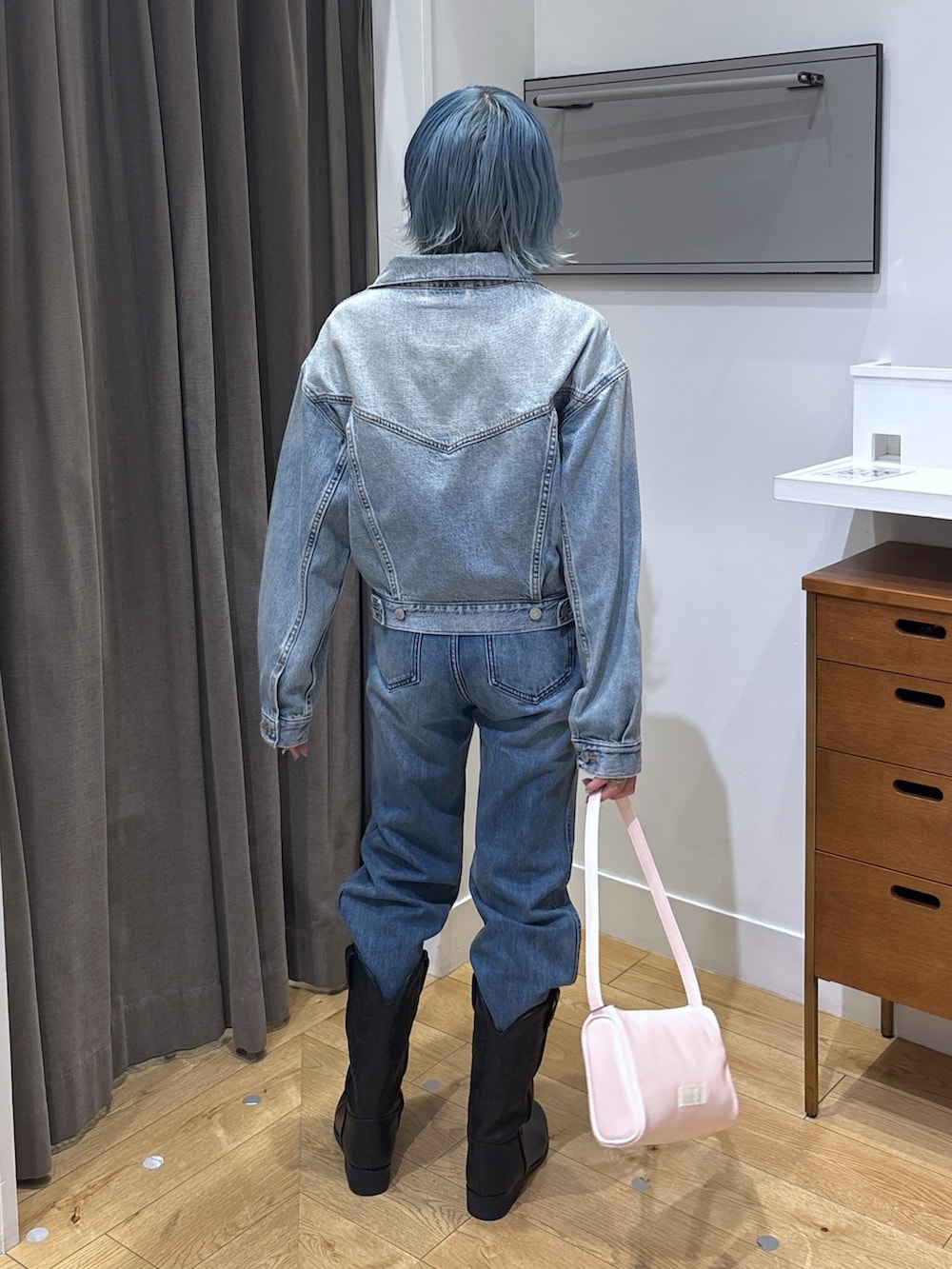 ブルー系のデニムジャケット、ブラック系のブーツ、ブルー系のデニムパンツを着用したレディースの春コーディネートの3枚目の写真