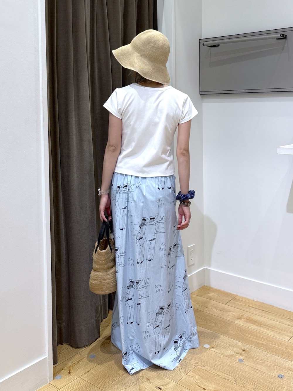 ベージュ系のトートバッグ、ブルー系のスカート、ホワイト系のTシャツ/カットソーを着用したレディースの夏コーディネートの4枚目の写真