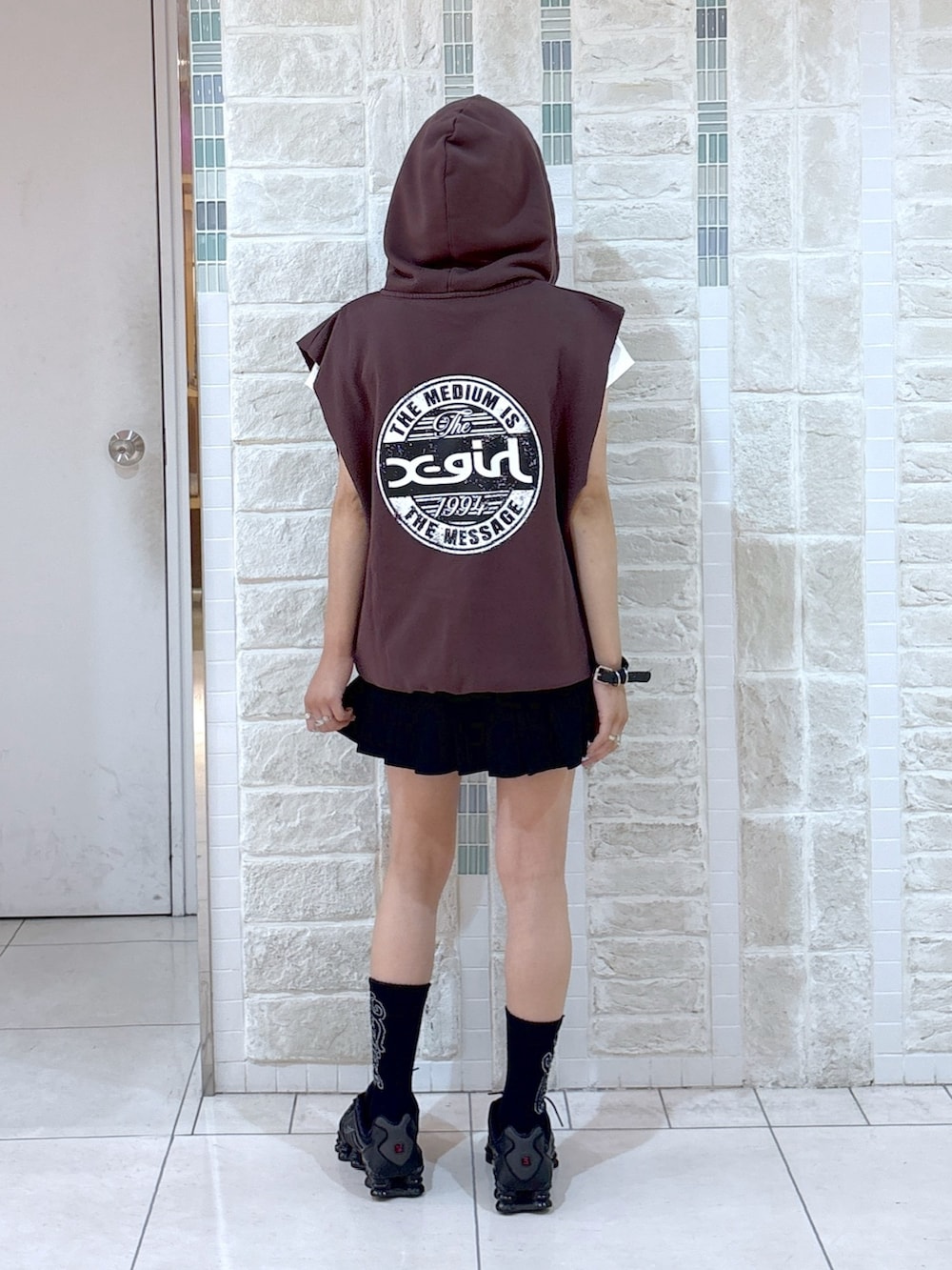 ブラウン系のベスト、ブラック系のスカート、ブラック系のハンドバッグを着用したレディースの夏コーディネートの5枚目の写真