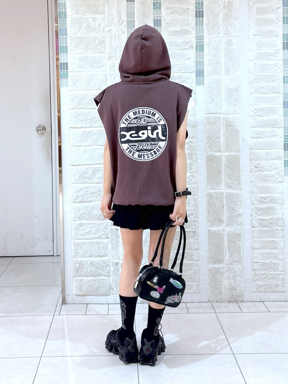 ブラウン系のベスト、ブラック系のスカート、ブラック系のハンドバッグを着用したレディースの夏コーディネートの2枚目の写真