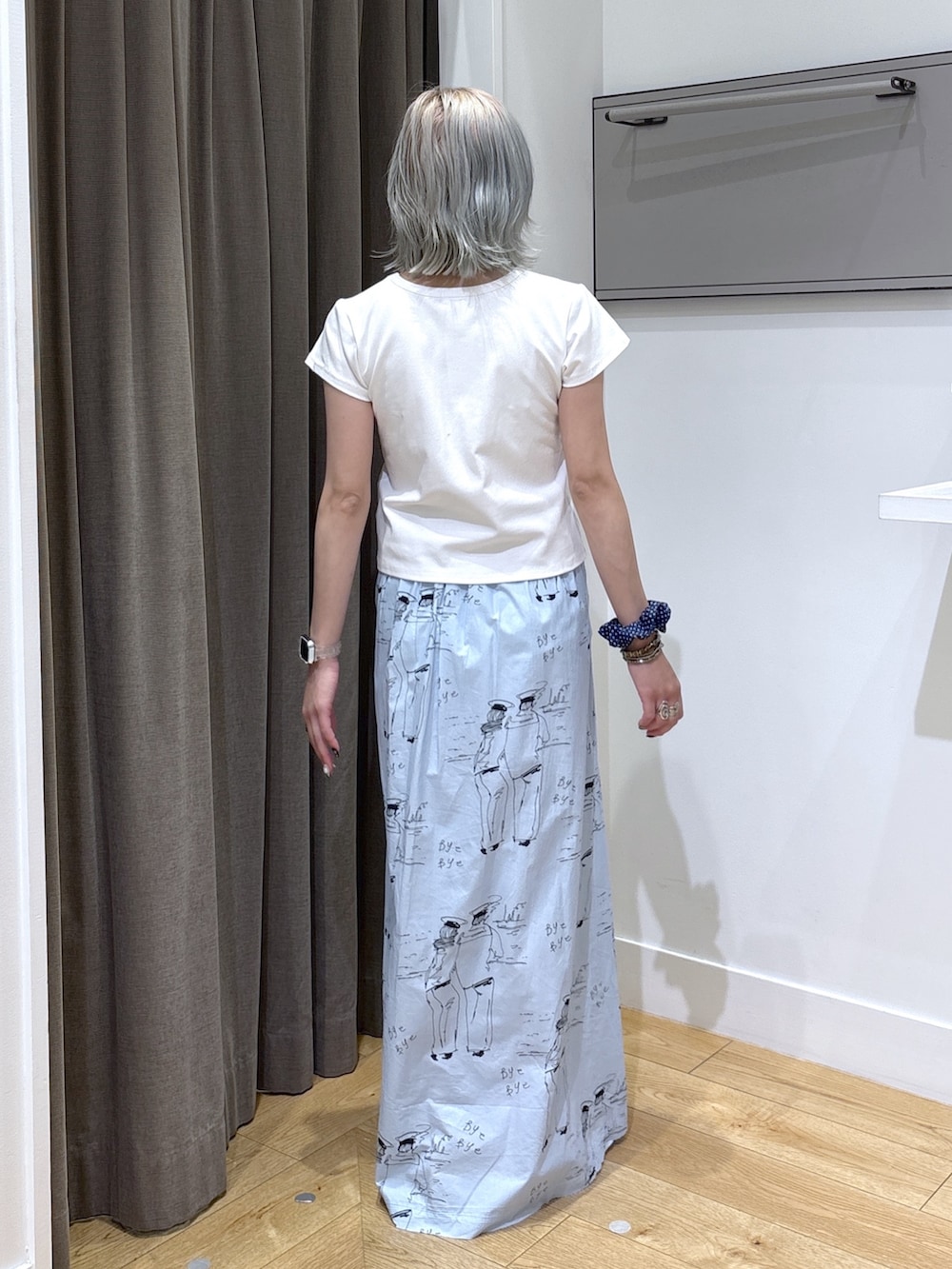 ベージュ系のトートバッグ、ブルー系のスカート、ホワイト系のTシャツ/カットソーを着用したレディースの夏コーディネートの8枚目の写真