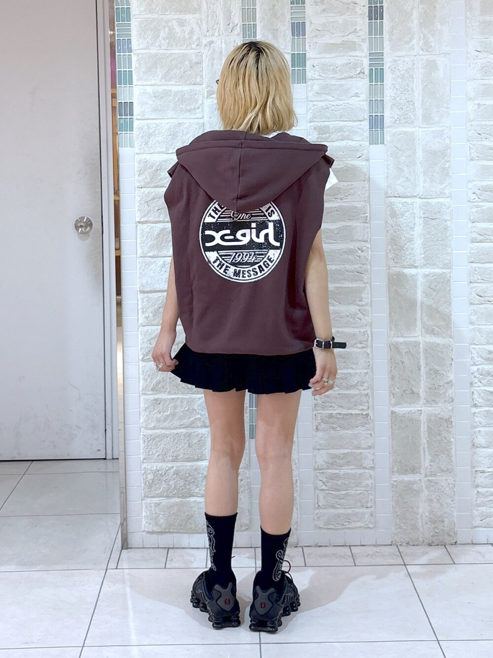 ブラウン系のベスト、ブラック系のスカート、ブラック系のハンドバッグを着用したレディースの夏コーディネートの6枚目の写真