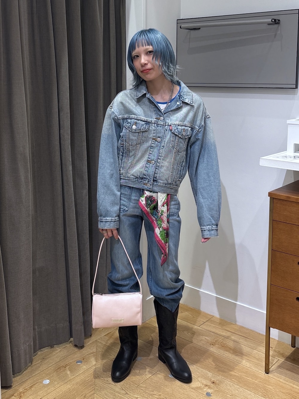 ブルー系のデニムジャケット、ブラック系のブーツ、ブルー系のデニムパンツを着用したレディースの春コーディネートの2枚目の写真