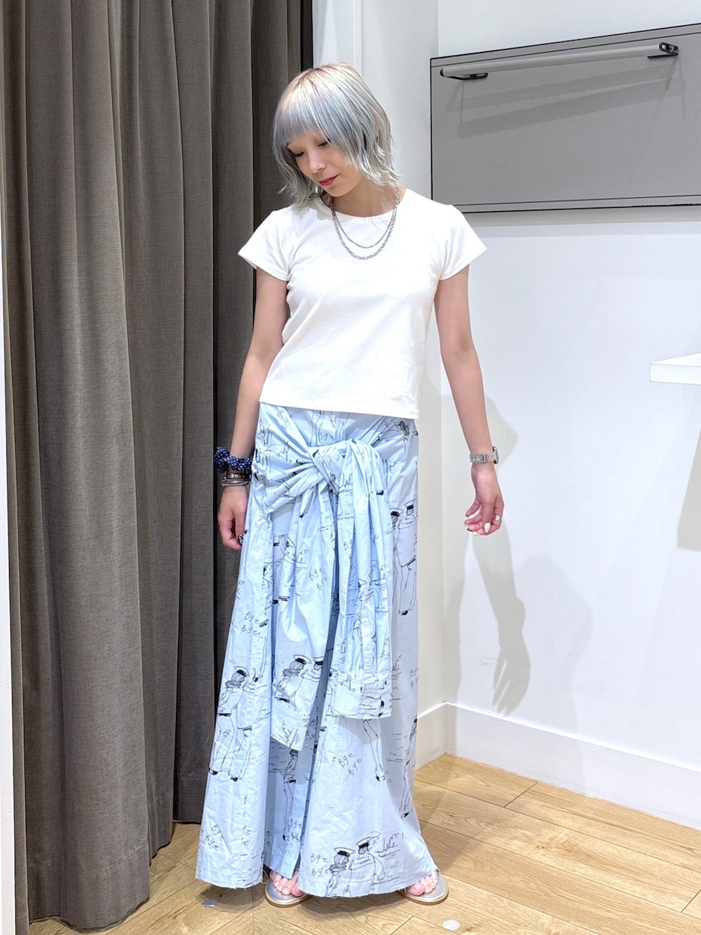 ベージュ系のトートバッグ、ブルー系のスカート、ホワイト系のTシャツ/カットソーを着用したレディースの夏コーディネートの5枚目の写真