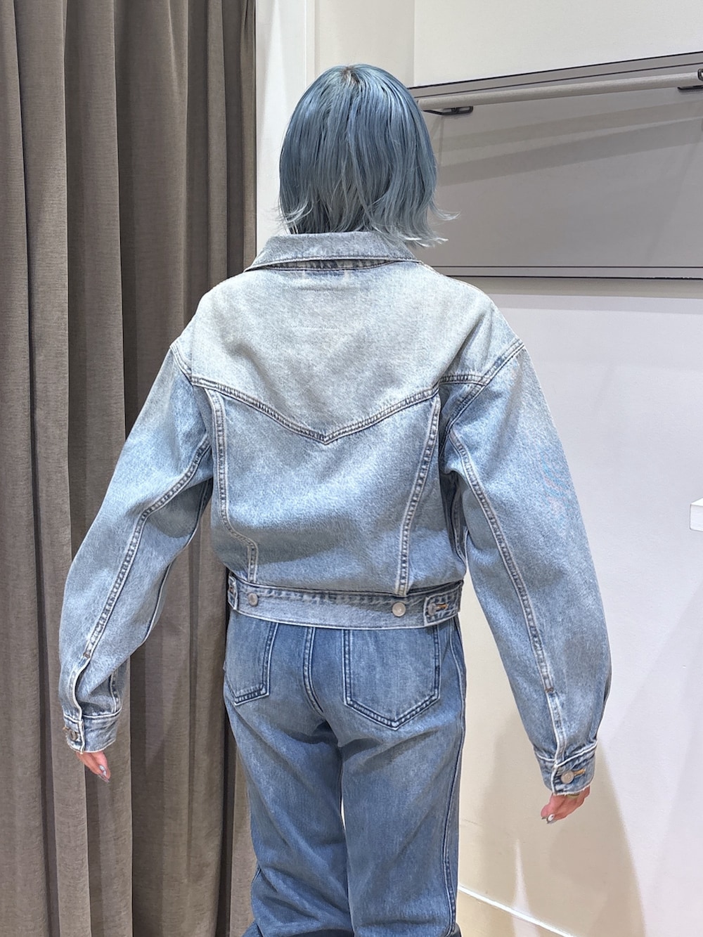 ブルー系のデニムジャケット、ブラック系のブーツ、ブルー系のデニムパンツを着用したレディースの春コーディネートの5枚目の写真