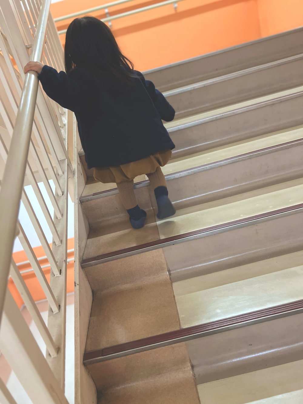 ブルー系のピーコート、ブルー系のドレスシューズ、ブラウン系のワンピースを着用したキッズの冬コーディネートの2枚目の写真