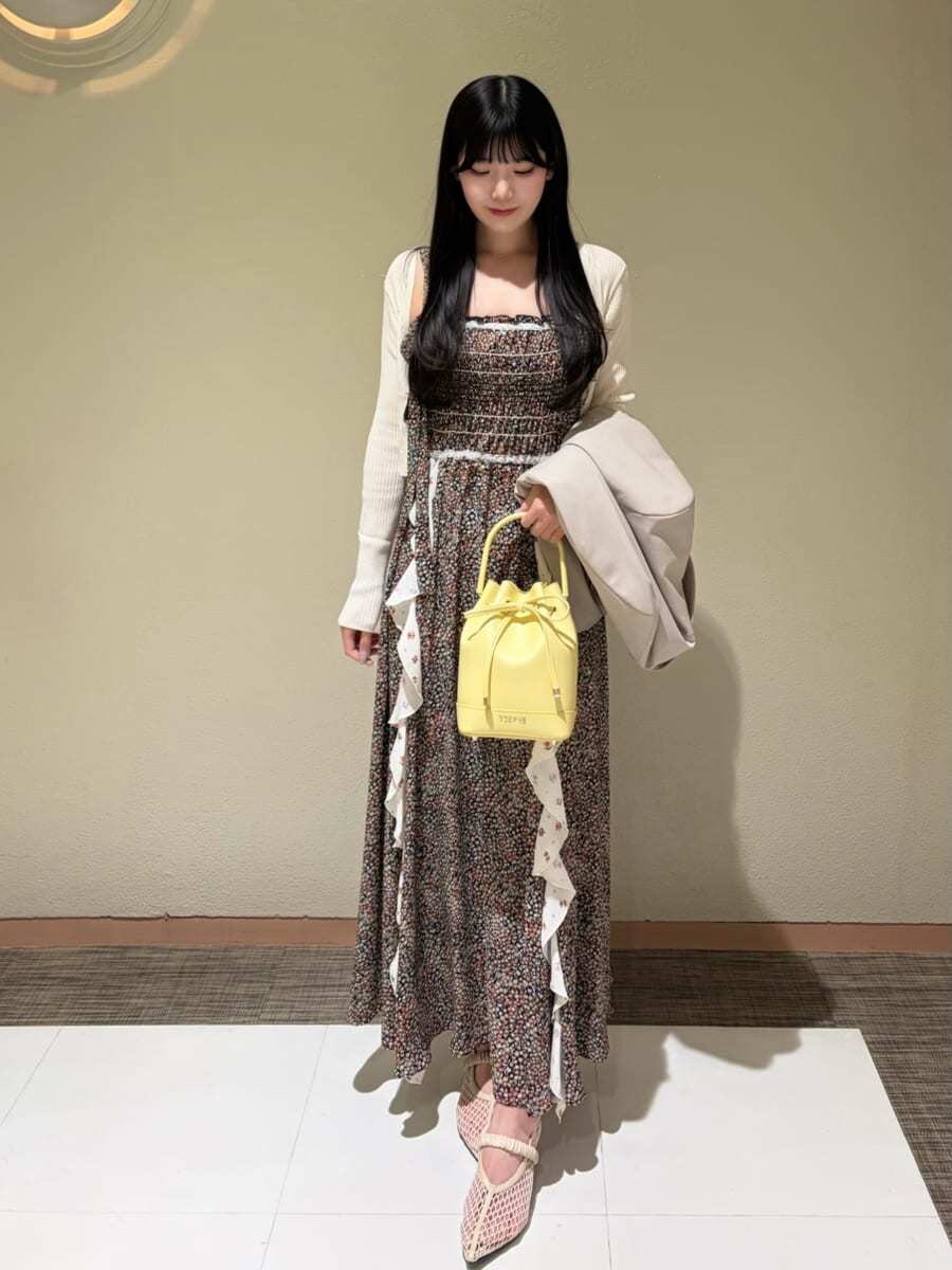 イエロー系のハンドバッグ、ホワイト系のカーディガン/ボレロ、ベージュ系のテーラードジャケットを着用したレディースの春コーディネートの7枚目の写真