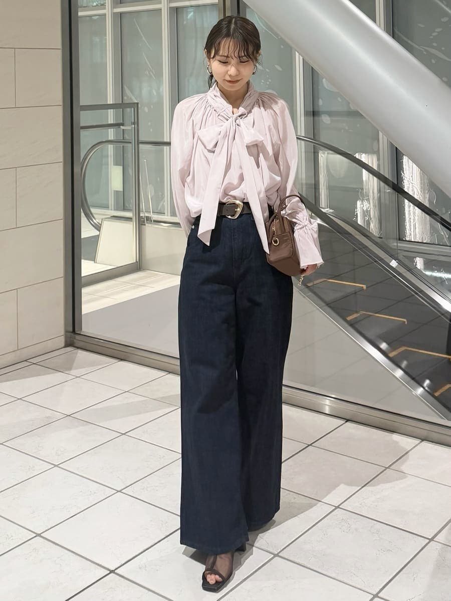 ブルー系のデニムパンツ、ブラウン系のハンドバッグ、ピンク系のシャツ/ブラウスを着用したレディースの冬コーディネートの2枚目の写真