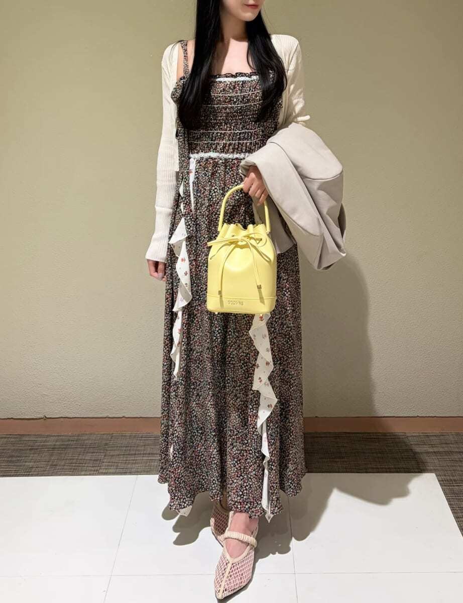 イエロー系のハンドバッグ、ホワイト系のカーディガン/ボレロ、ベージュ系のテーラードジャケットを着用したレディースの春コーディネートの6枚目の写真