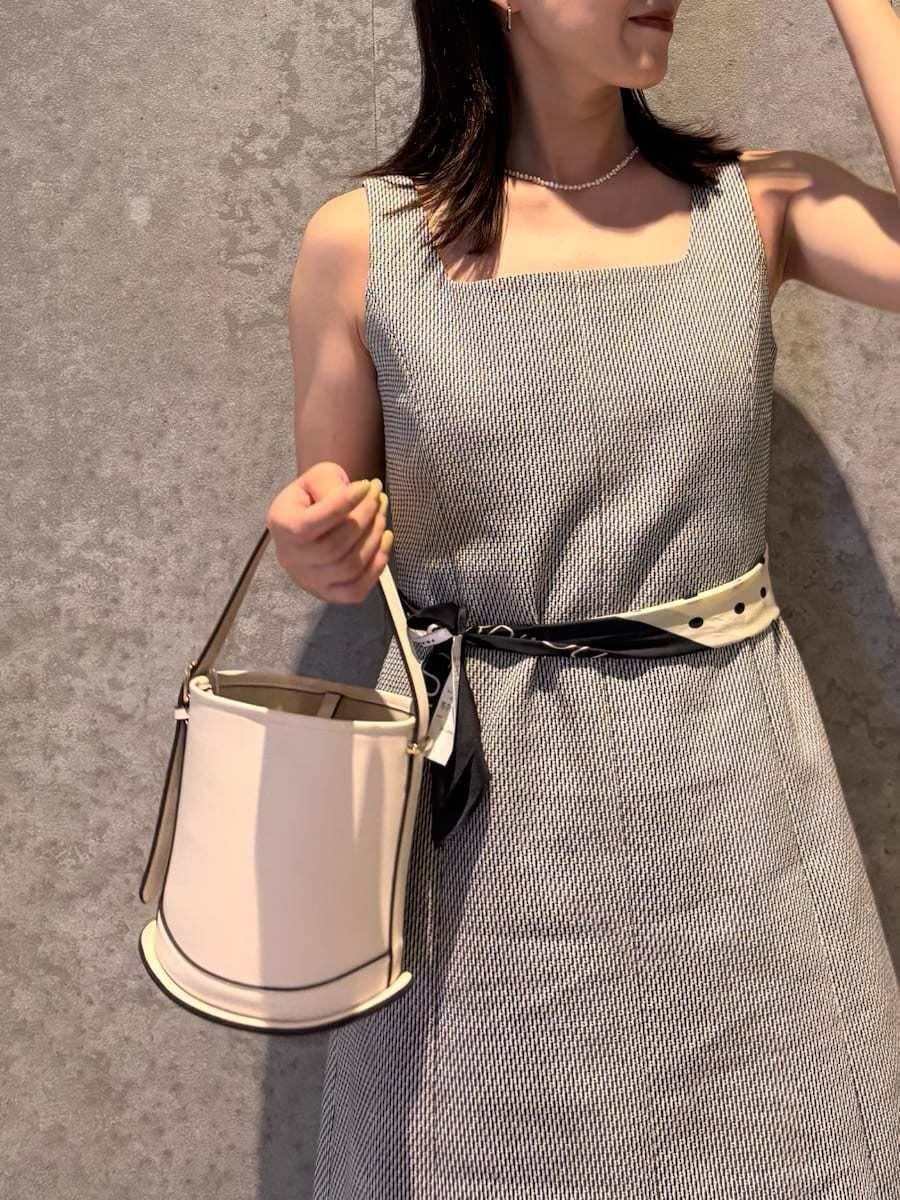 ホワイト系のハンドバッグ、ブラック系のサンダルを着用したレディースの春コーディネートの6枚目の写真