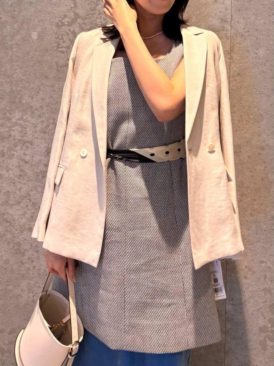 ホワイト系のハンドバッグ、ブラック系のサンダルを着用したレディースの春コーディネートの2枚目の写真