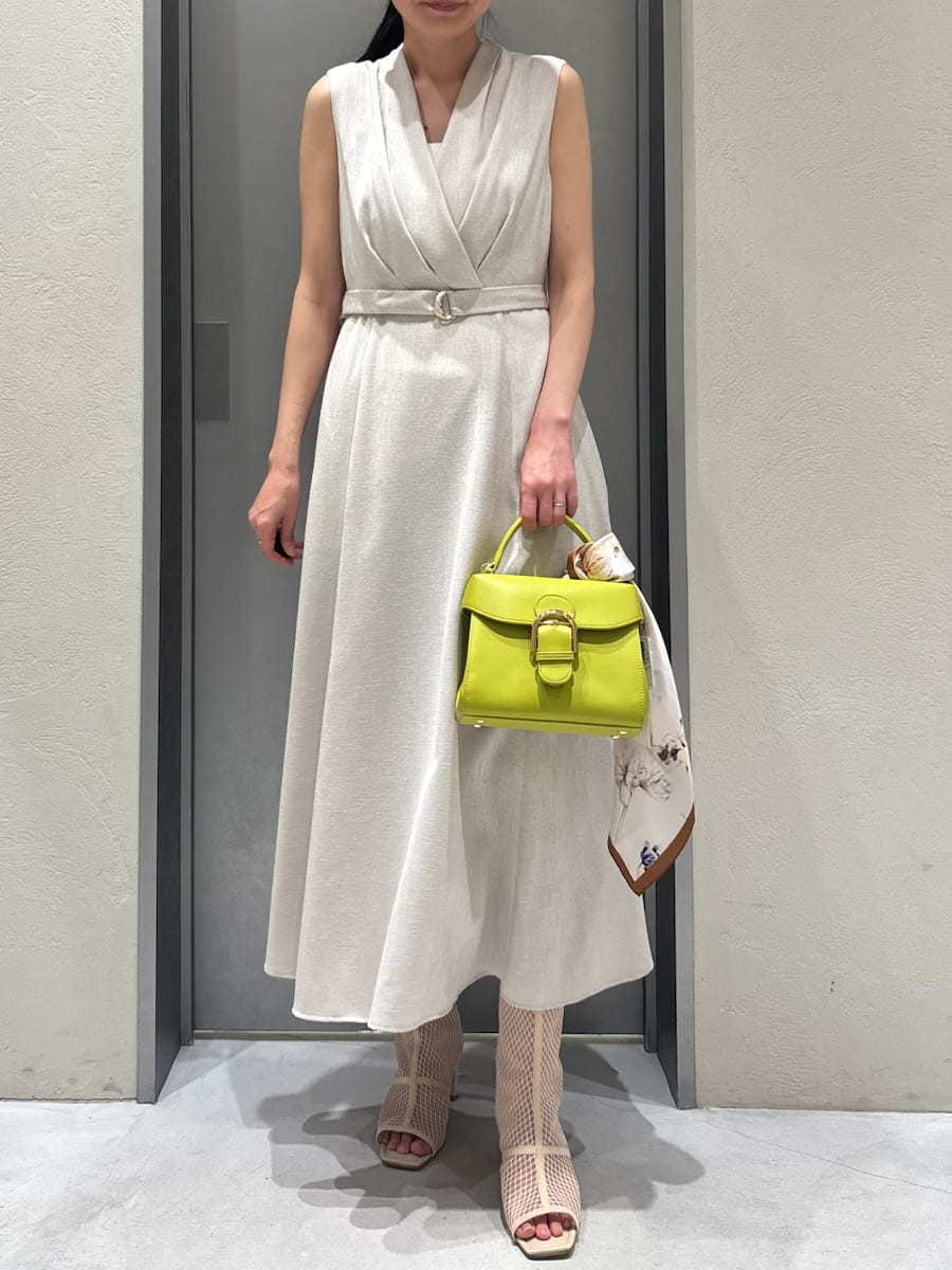 ベージュ系のワンピース、ホワイト系のカーディガン/ボレロ、グリーン系のハンドバッグを着用したレディースの春コーディネートの2枚目の写真