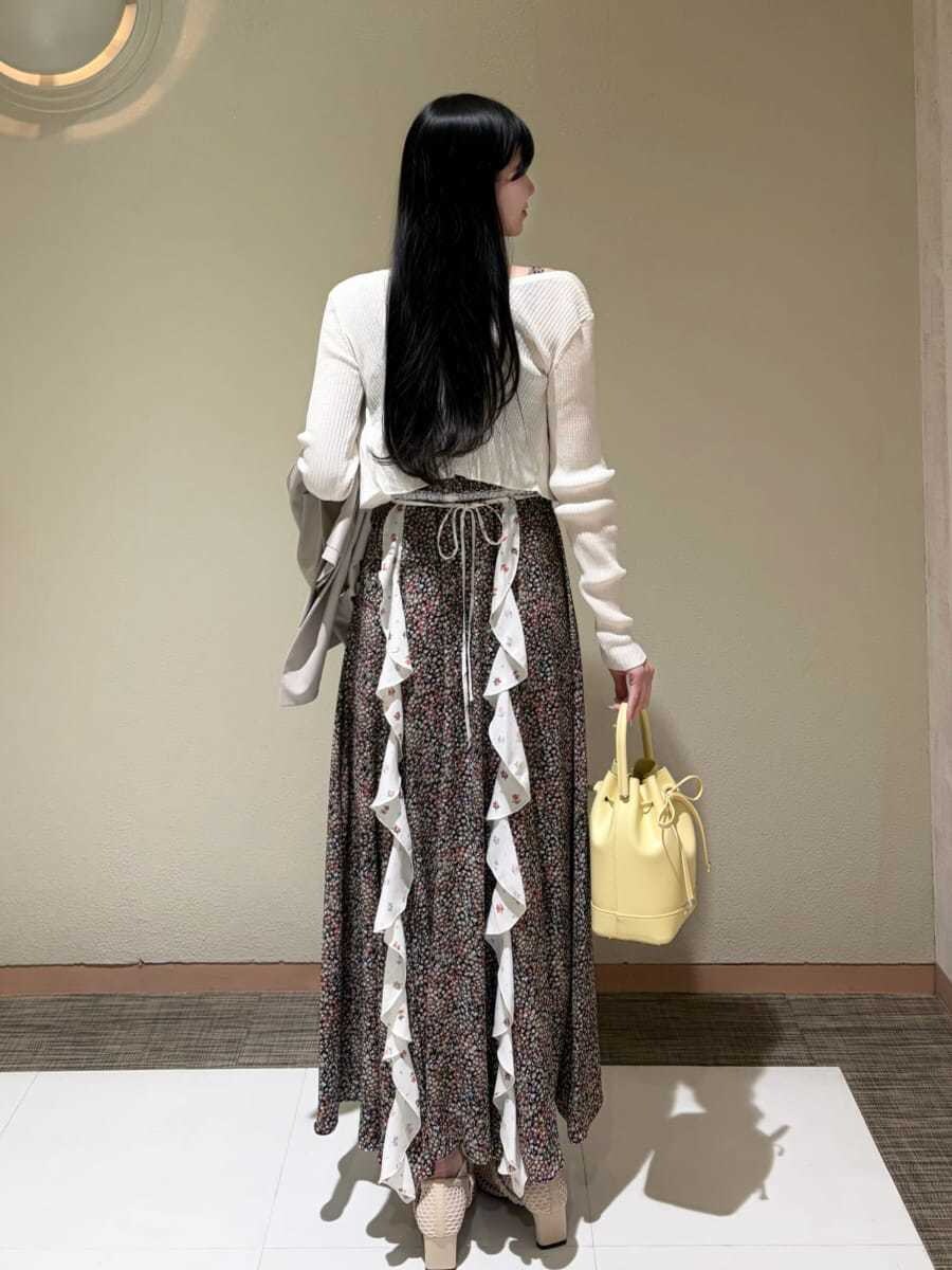 イエロー系のハンドバッグ、ホワイト系のカーディガン/ボレロ、ベージュ系のテーラードジャケットを着用したレディースの春コーディネートの8枚目の写真