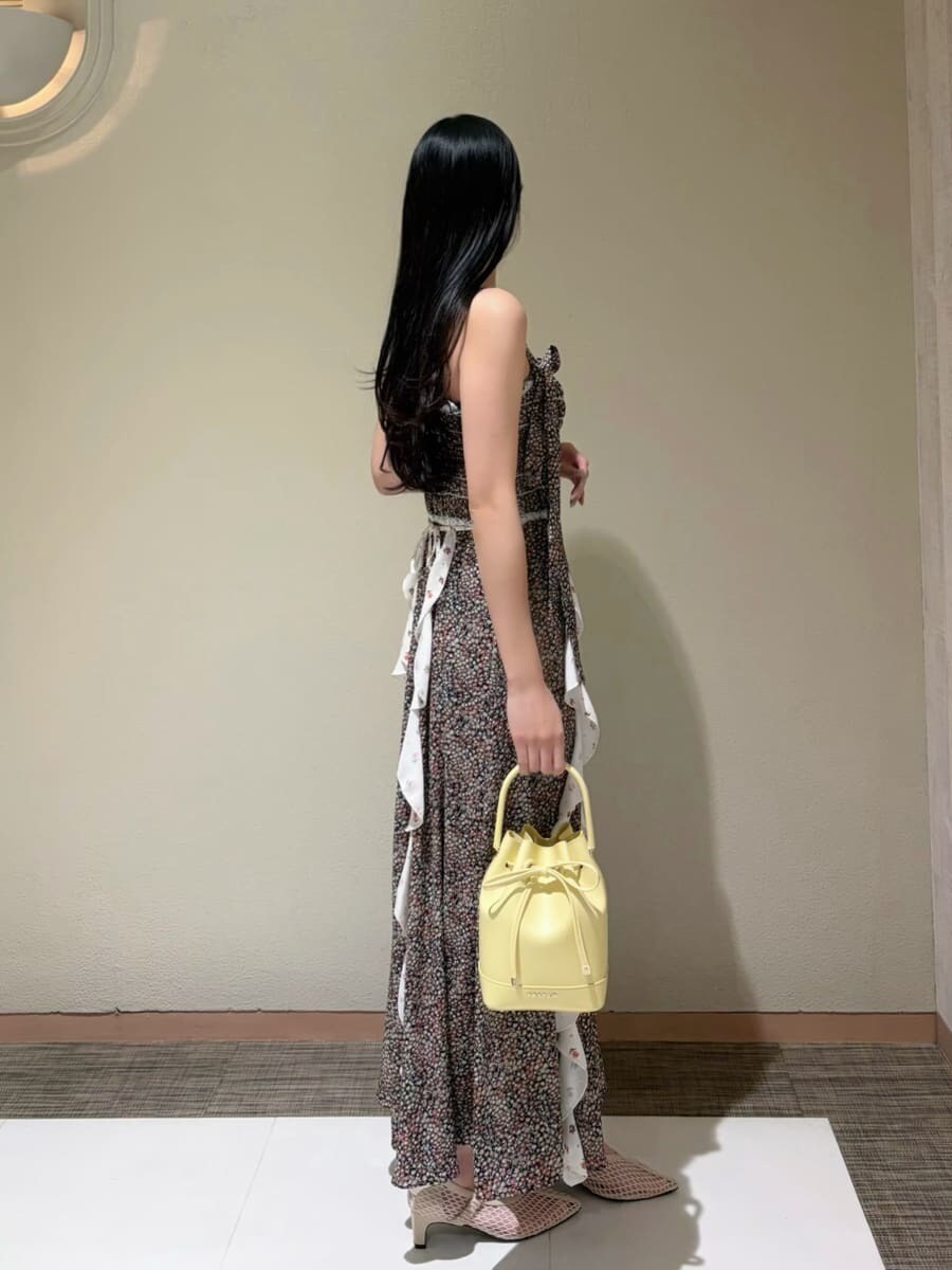 イエロー系のハンドバッグ、ホワイト系のカーディガン/ボレロ、ベージュ系のテーラードジャケットを着用したレディースの春コーディネートの4枚目の写真