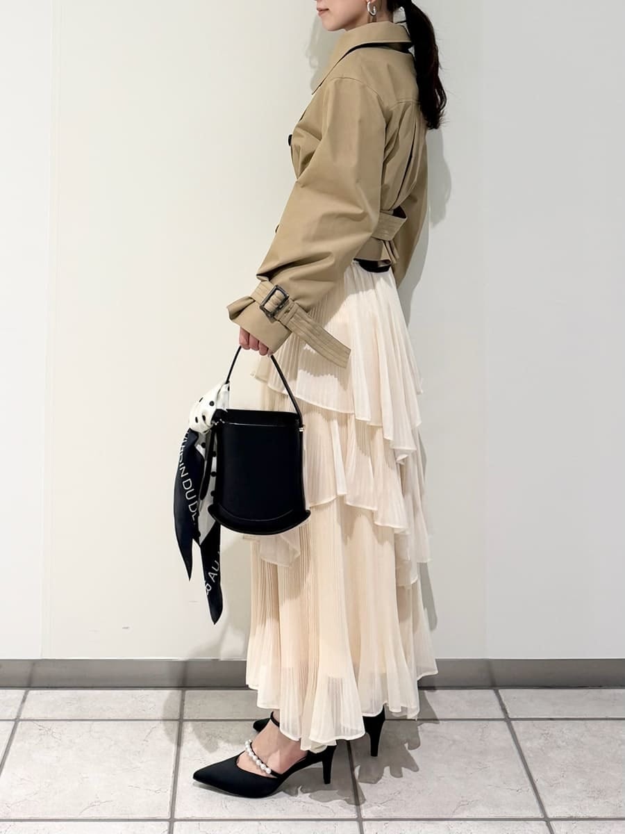 ベージュ系のスカート、ベージュ系のトレンチコート、ブラック系のニット/セーターを着用したレディースの冬コーディネートの9枚目の写真