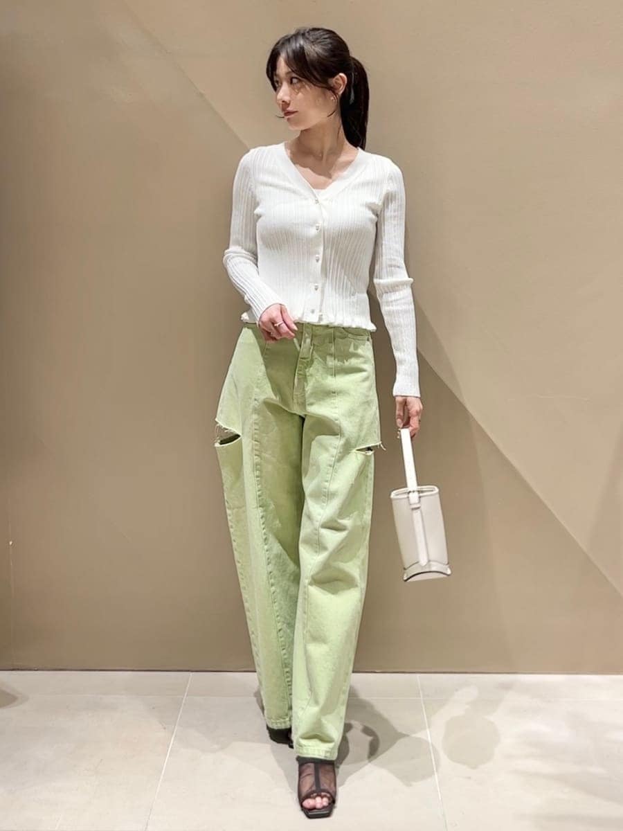 グリーン系のデニムパンツ、ホワイト系のニット/セーター、ホワイト系のハンドバッグを着用したレディースの冬コーディネートの2枚目の写真