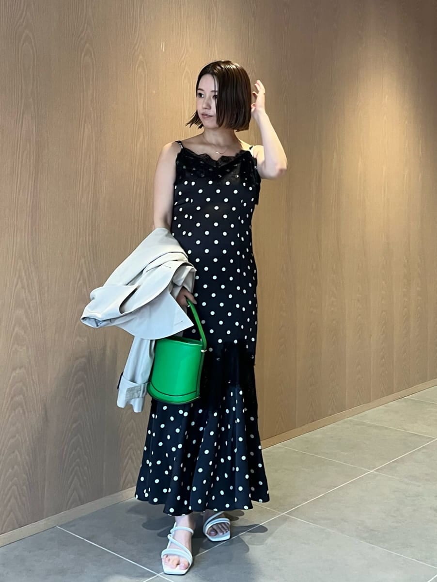 ベージュ系のトレンチコート、ブラック系のワンピース、グリーン系のハンドバッグを着用したレディースの春コーディネートの3枚目の写真