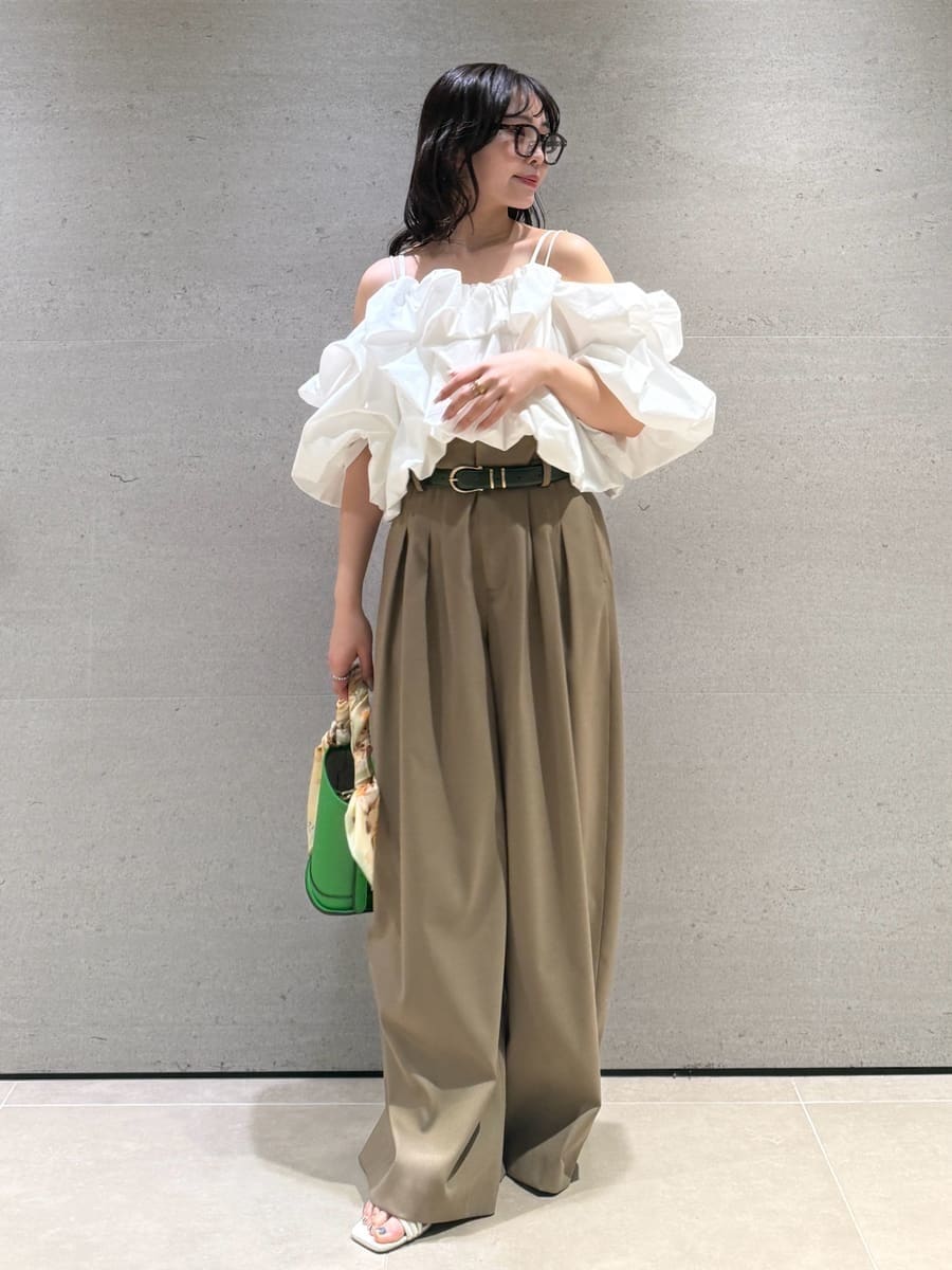 グリーン系のハンドバッグ、ホワイト系のサンダル、ホワイト系のシャツ/ブラウスを着用したレディースの冬コーディネートの2枚目の写真