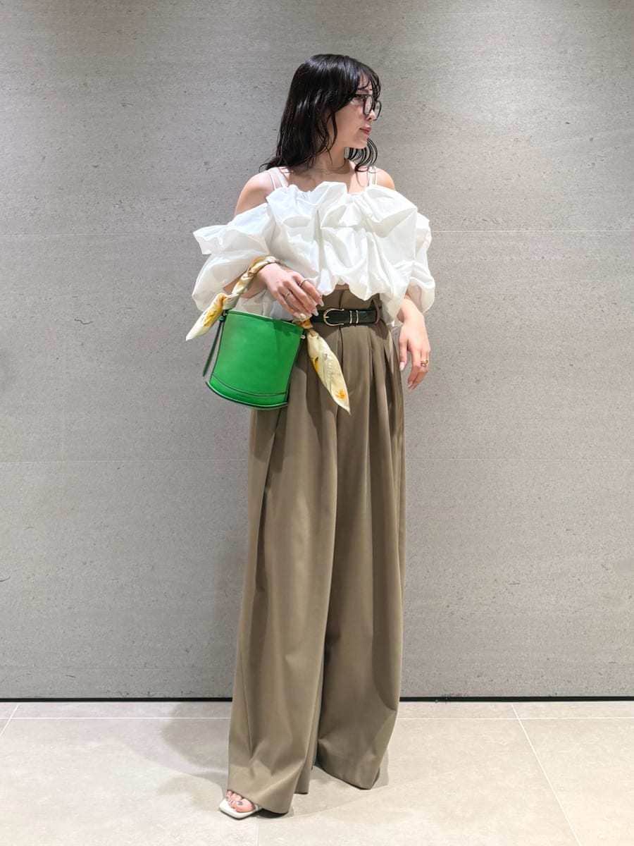 グリーン系のハンドバッグ、ホワイト系のサンダル、ホワイト系のシャツ/ブラウスを着用したレディースの冬コーディネートの3枚目の写真