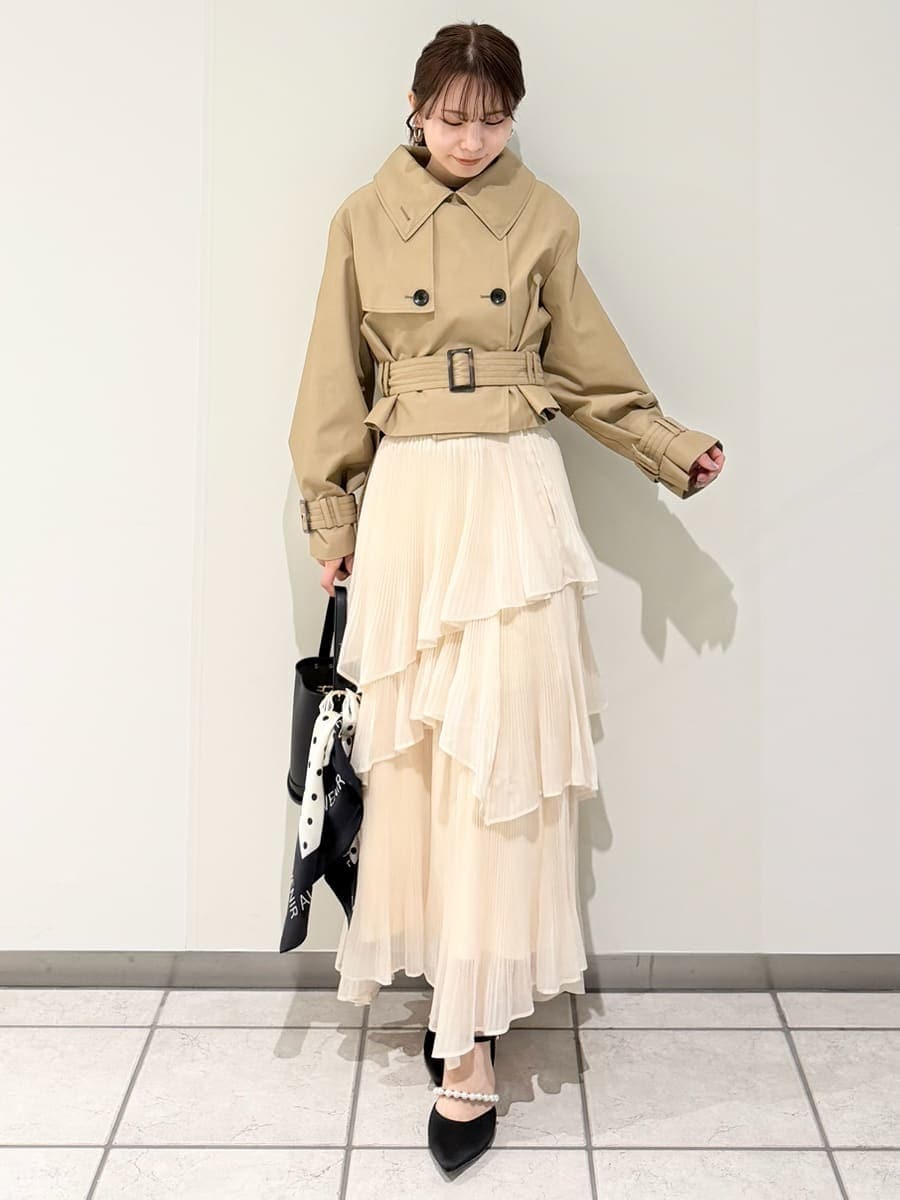 ベージュ系のスカート、ベージュ系のトレンチコート、ブラック系のニット/セーターを着用したレディースの冬コーディネートの10枚目の写真