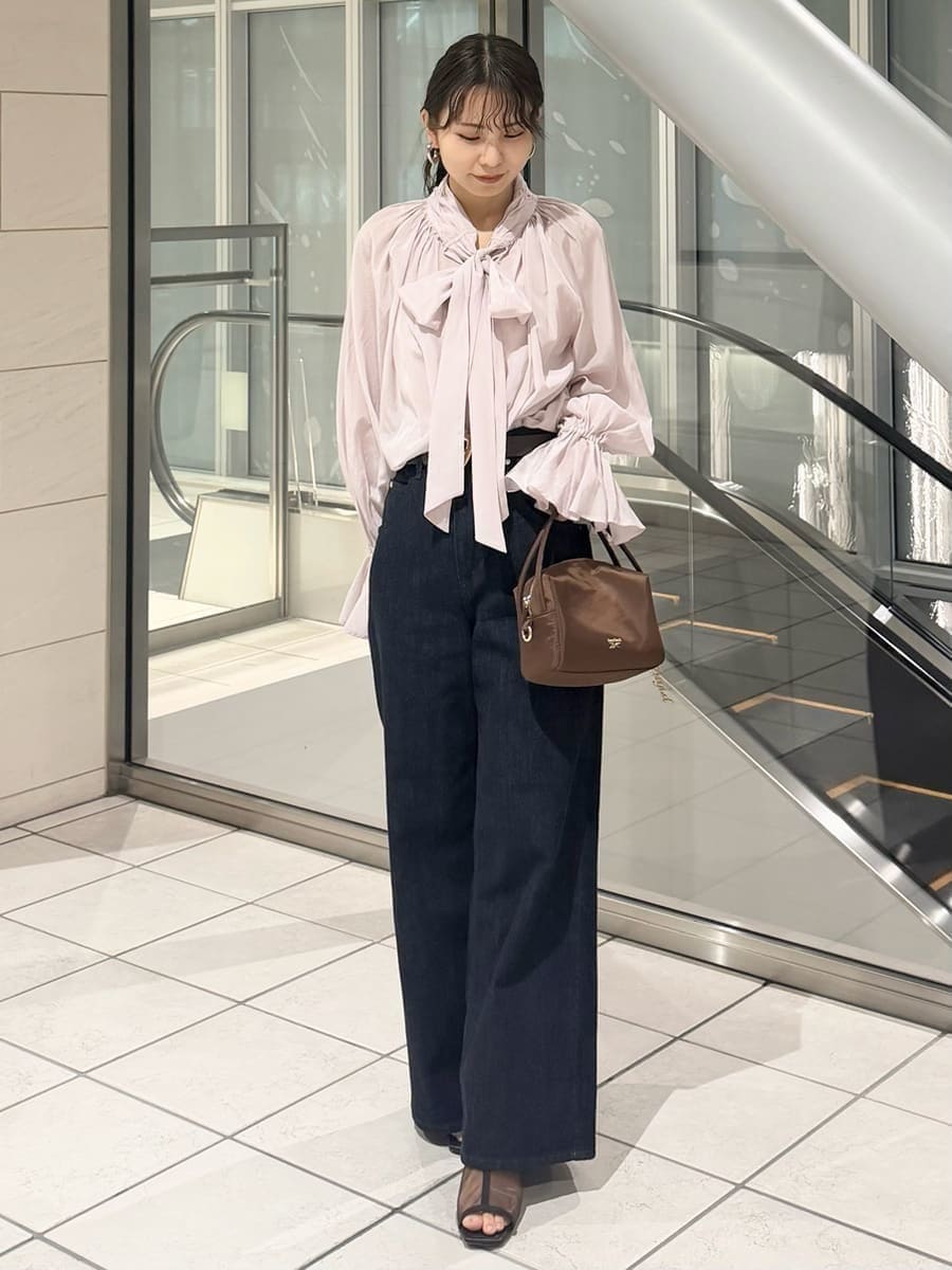 ブルー系のデニムパンツ、ブラウン系のハンドバッグ、ピンク系のシャツ/ブラウスを着用したレディースの冬コーディネートの6枚目の写真