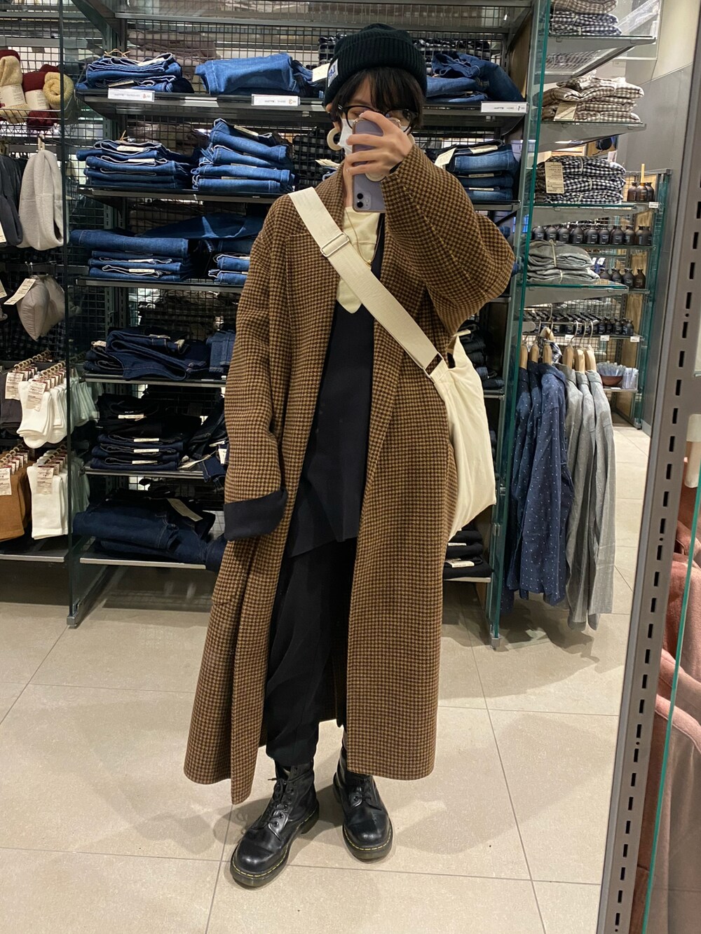 ブラック系のニット/セーター、ホワイト系のTシャツ/カットソー、ホワイト系のショルダーバッグを着用したレディースの冬コーディネートの2枚目の写真