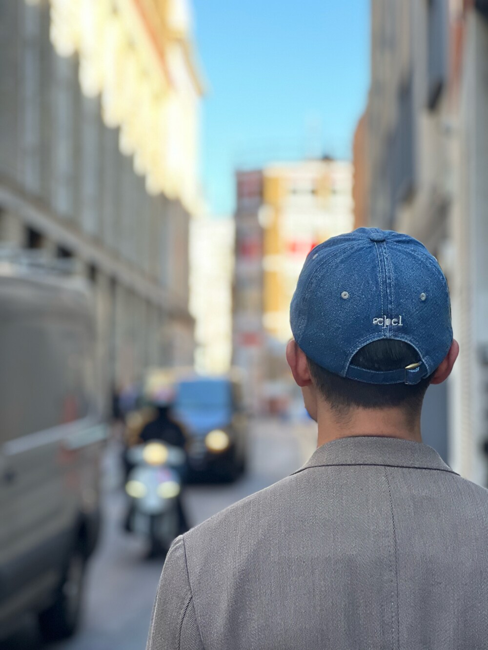 グレー系のテーラードジャケット、ブルー系のキャップを着用したメンズの夏コーディネートの2枚目の写真