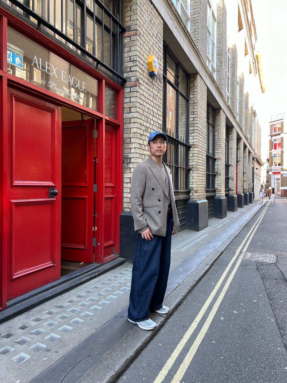 ベージュ系のテーラードジャケット、シルバー系のスニーカー、ブルー系のキャップを着用したメンズの夏コーディネートの2枚目の写真