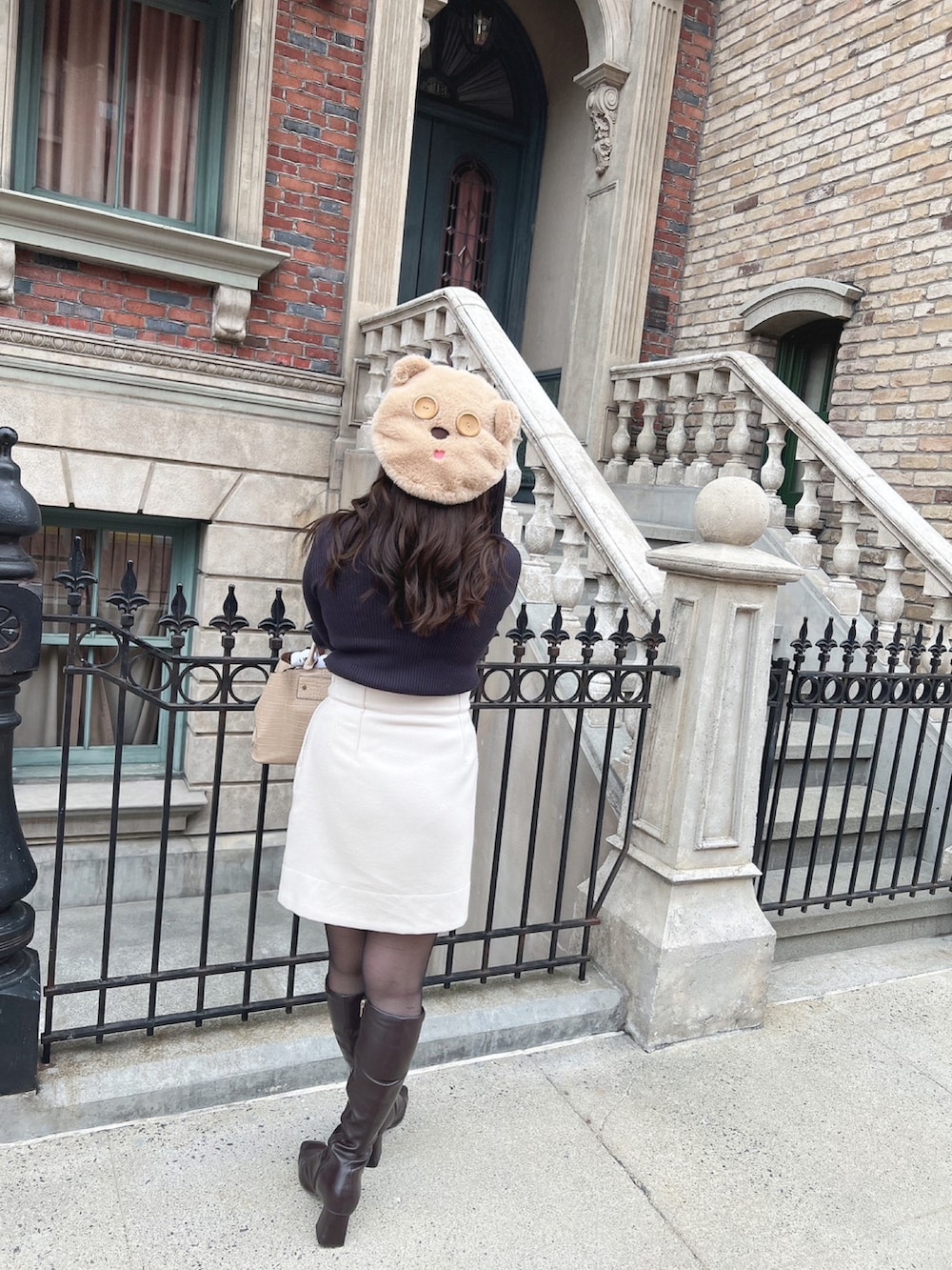 パープル系のニット/セーター、ホワイト系のスカートを着用したレディースの冬コーディネートの2枚目の写真