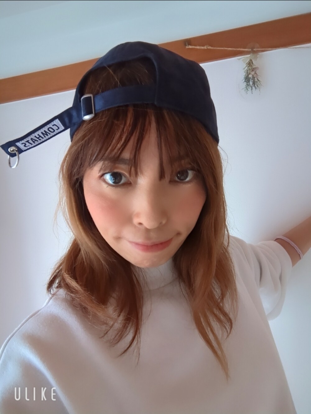 ブルー系のキャップを着用したレディースの春コーディネートの2枚目の写真