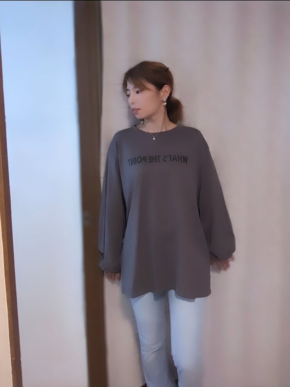 グレー系のトップス、シルバー系のネックレスを着用したレディースの秋コーディネートの2枚目の写真