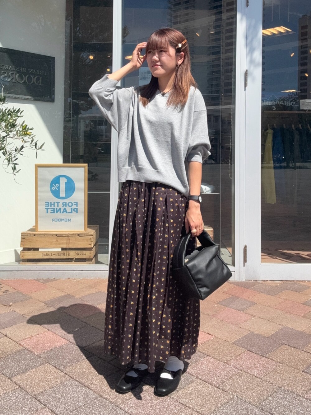 ブラック系のスカート、ブラック系のハンドバッグ、グレー系のニット/セーターを着用したレディースの秋コーディネートの2枚目の写真