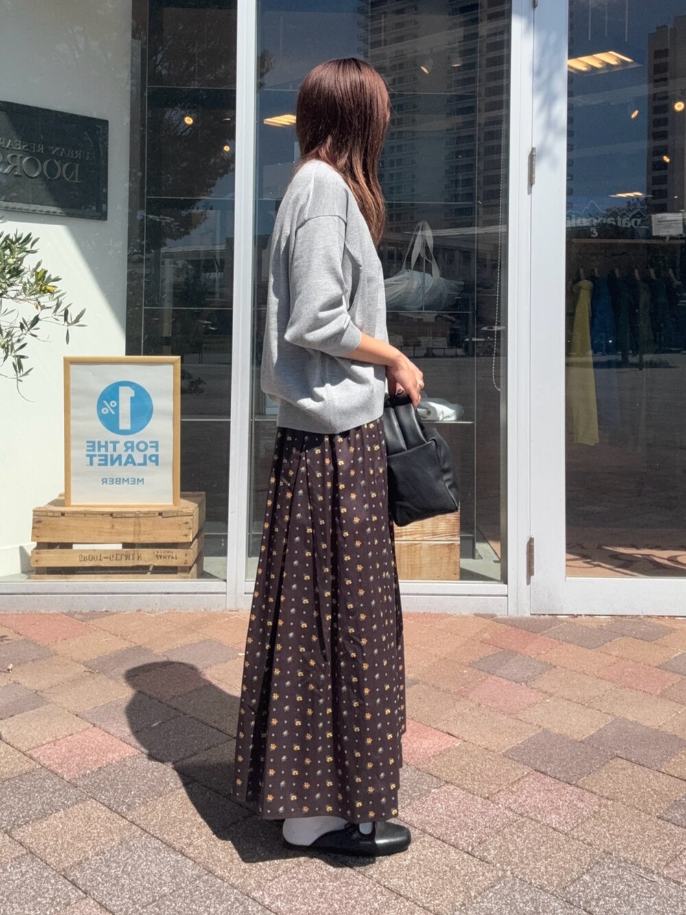 ブラック系のスカート、ブラック系のハンドバッグ、グレー系のニット/セーターを着用したレディースの秋コーディネートの4枚目の写真