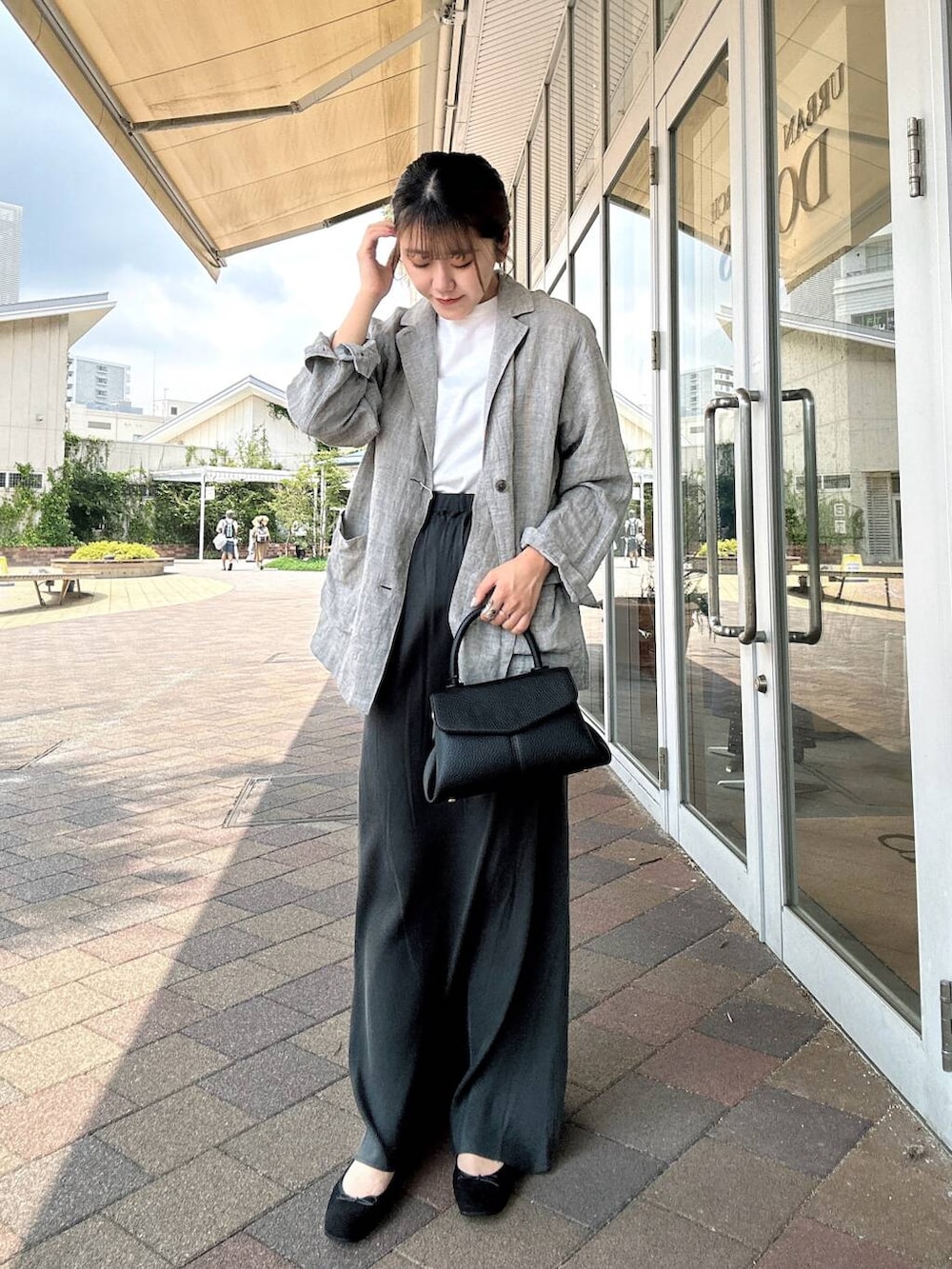 ホワイト系のTシャツ/カットソー、ブラック系のバレエシューズ、ブラック系のショルダーバッグを着用したレディースの夏コーディネートの2枚目の写真