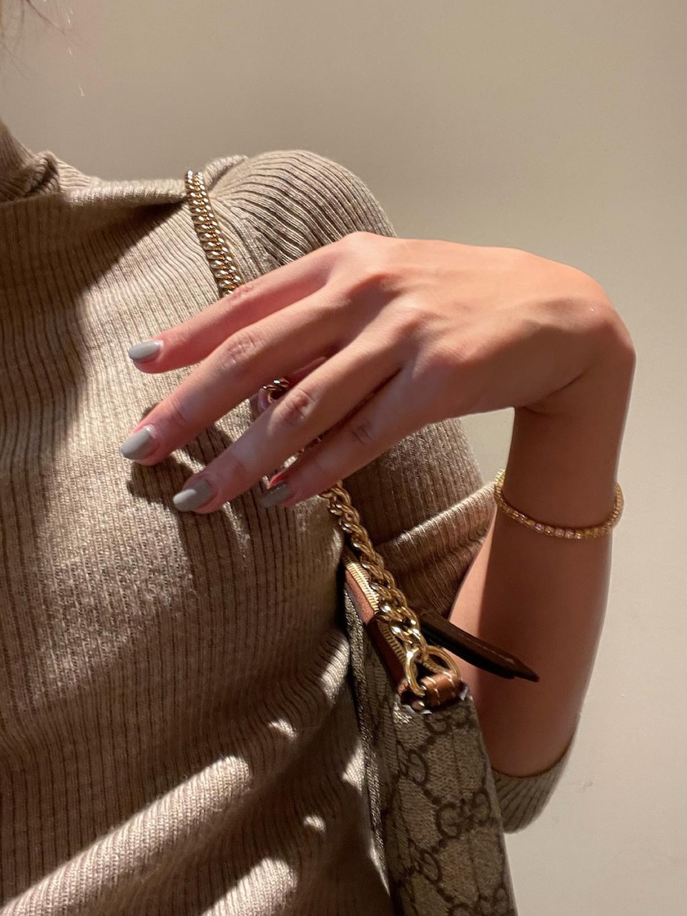 ベージュ系のニット/セーター、ブラウン系のハンドバッグ、ブラック系のメガネを着用したレディースの冬コーディネートの2枚目の写真