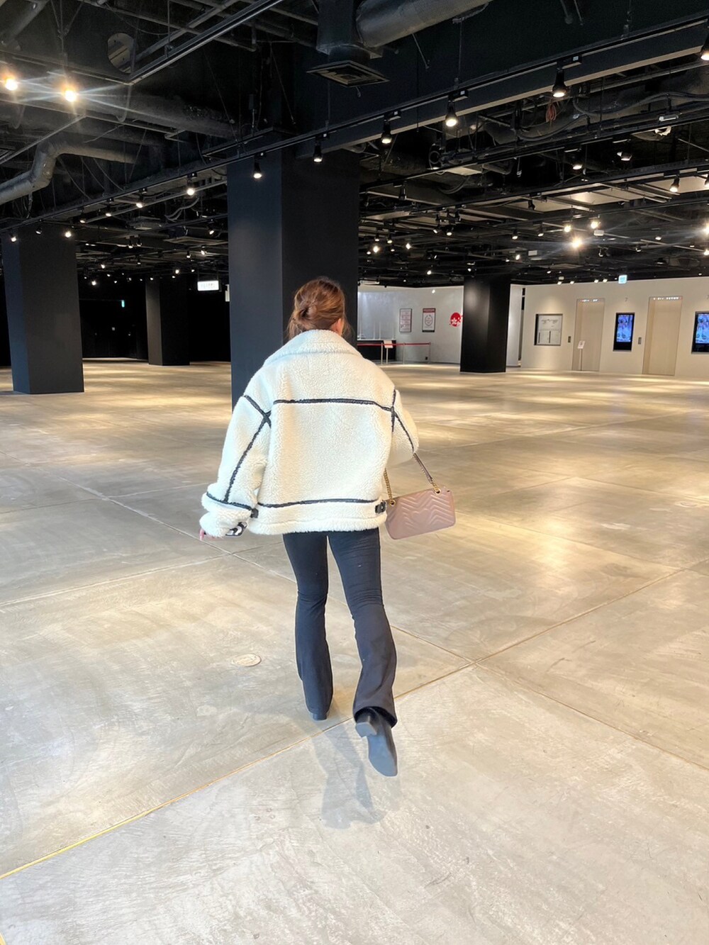 ホワイト系のムートンコート、ピンク系のショルダーバッグを着用したレディースの冬コーディネートの2枚目の写真