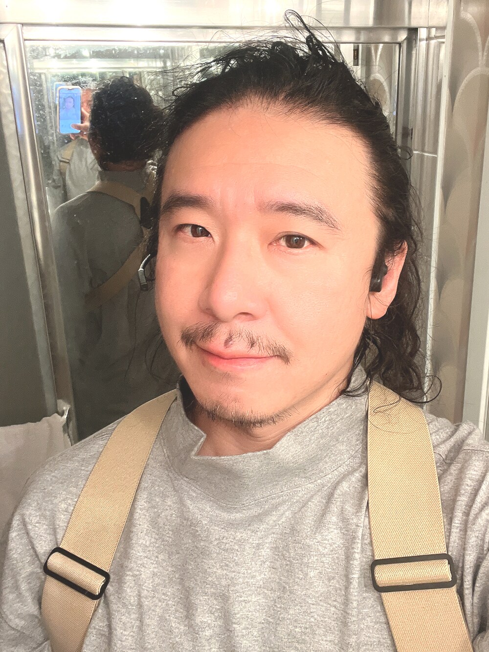 グレー系のスニーカー、グレー系のTシャツ/カットソー、グリーン系のカーゴパンツを着用したメンズの秋コーディネートの2枚目の写真
