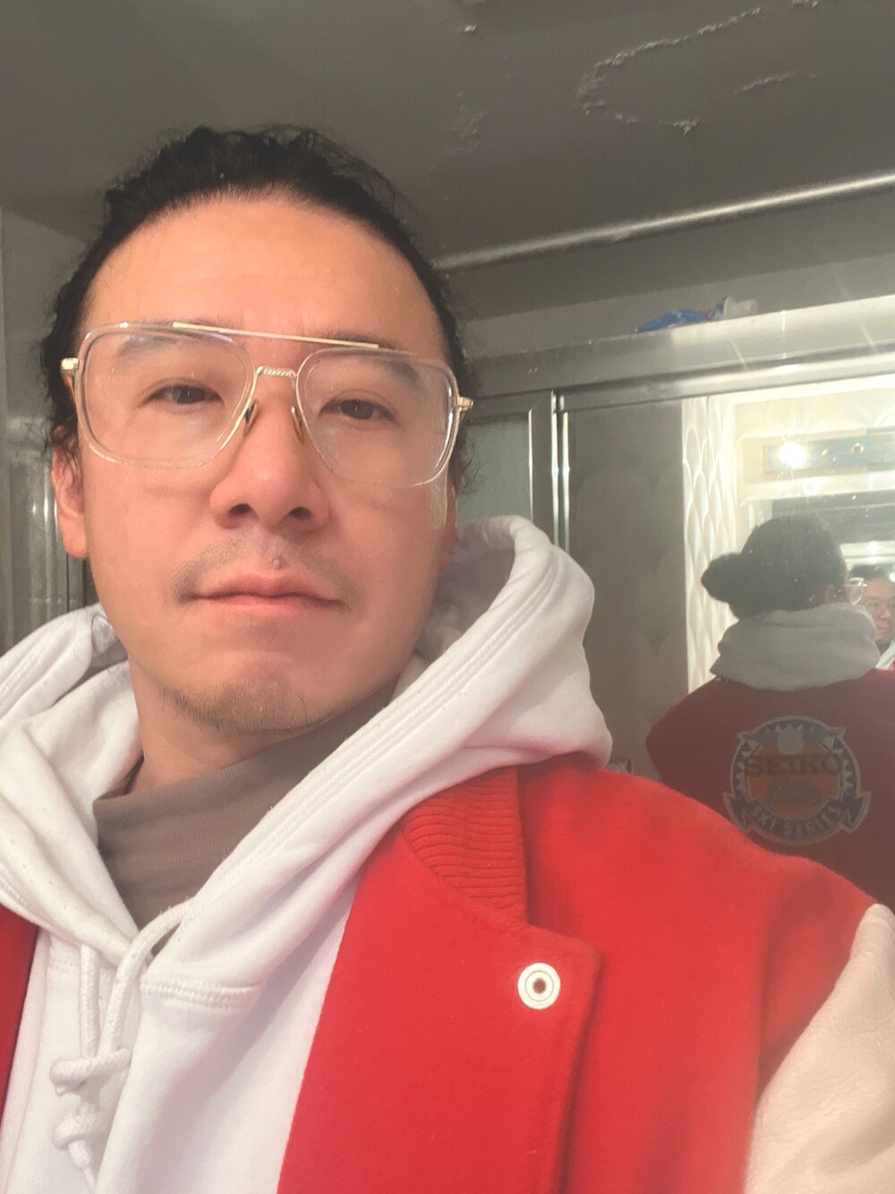 ブルー系のデニムパンツ、ホワイト系のスニーカー、レッド系のスタジャンを着用したメンズの冬コーディネートの2枚目の写真