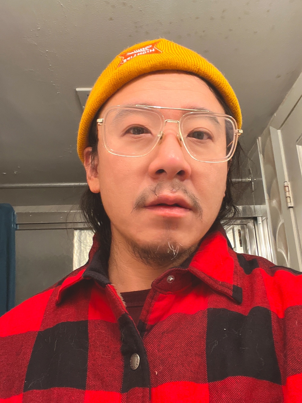 ブルー系のデニムパンツ、ブルー系のスニーカー、レッド系のチェスターコートを着用したメンズの秋コーディネートの2枚目の写真