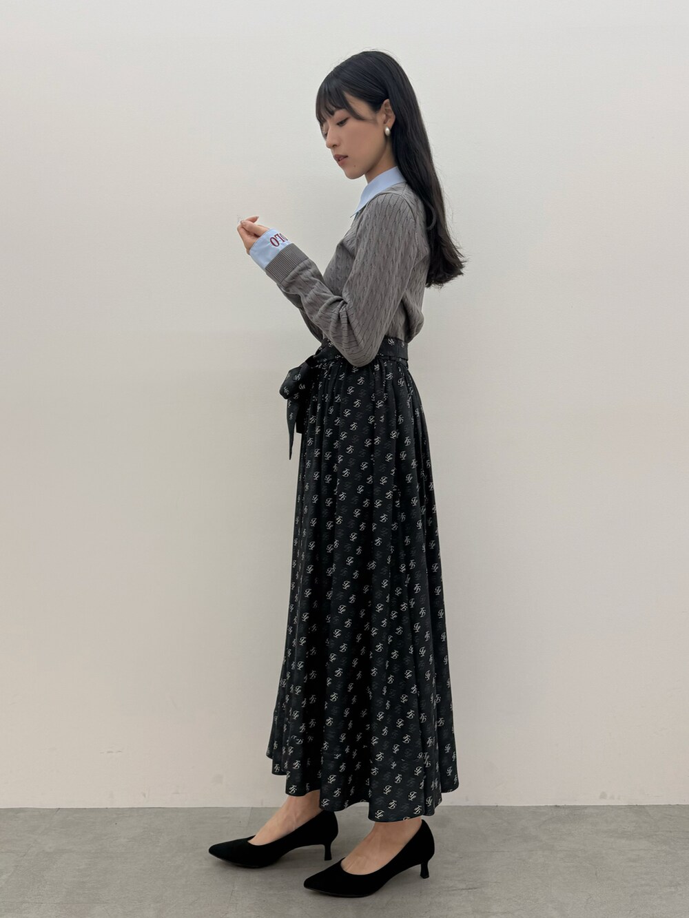ブラック系のスカート、グレー系のニット/セーターを着用したレディースの夏コーディネートの2枚目の写真